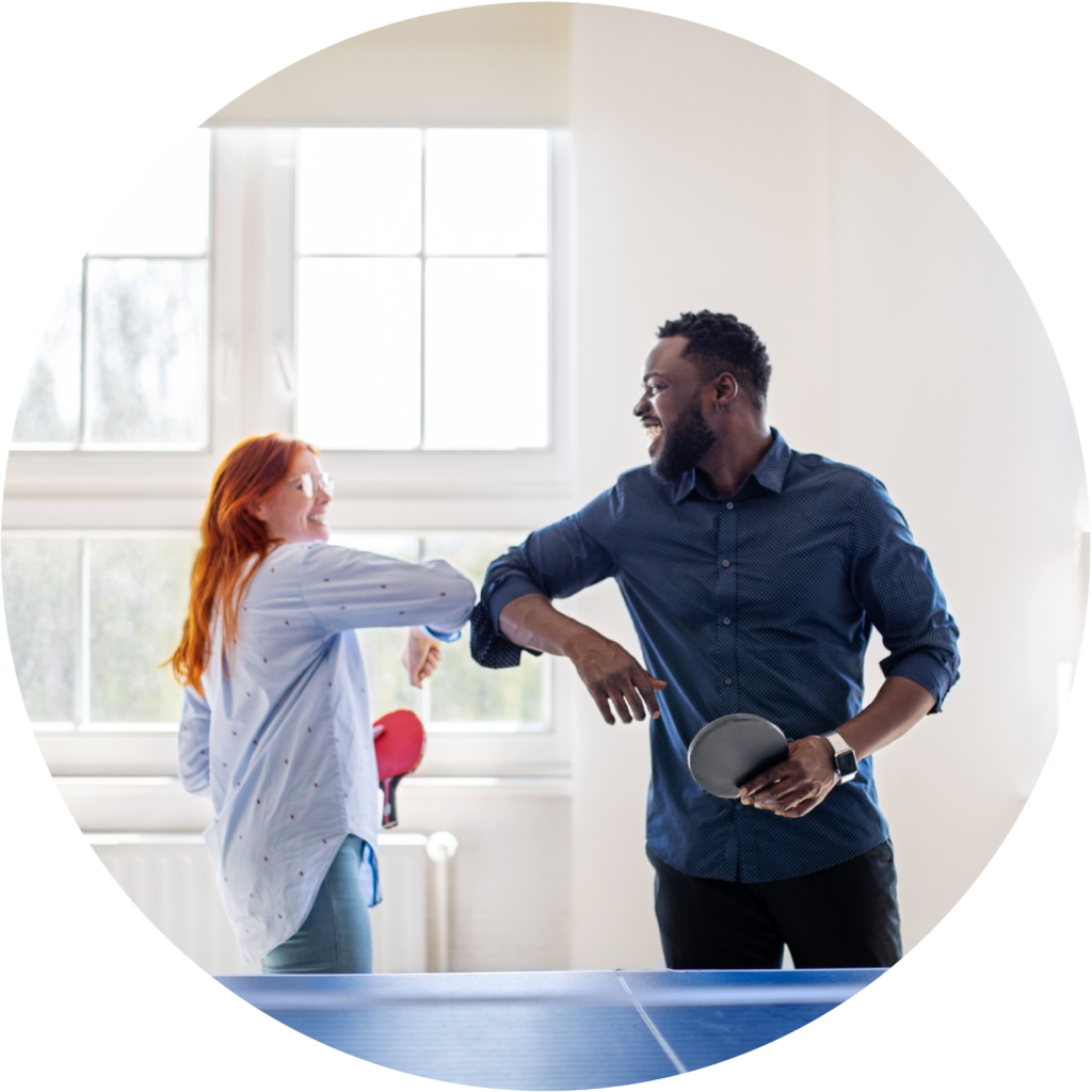 Two young people playing ping pong bumping elbows